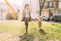 Italia, Mujer con perro paseando en un entorno urbano - foto de stock