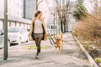 Italy, Woman with dog walking along street — Stock Photo