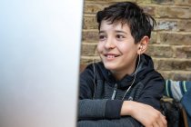 Royaume-Uni, garçon souriant assistant à des cours en ligne — Photo de stock