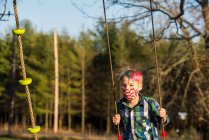 Canada, Ontario, Boy in face mask on swing — Stock Photo