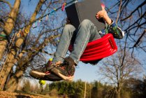 Canada, Ontario, Low angle view of boy with book on swing — Stock Photo