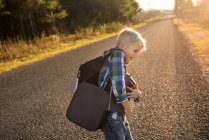 Canadá, Ontário, menino sorridente com livros sobre estrada rural ao pôr do sol — Fotografia de Stock