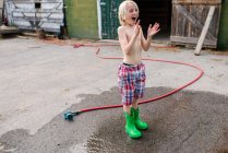 Канада, Онтарио, Кингстон, Мальчик без рубашки играет со шлангом для садоводства — стоковое фото