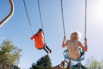 USA, CA, San Francisco, Brother and sister on swings against sky — Stock Photo