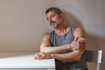 França, Homem com bandagem no braço sentado à mesa — Fotografia de Stock