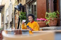 Itália, Toscana, Pistoia, Mulher sentado no café ao ar livre e usando telefone inteligente — Fotografia de Stock