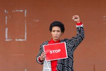 Italia, Toscana, Pistoia, Mujer sosteniendo stop signo y levantando el puño - foto de stock