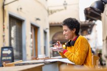 Italy, Tuscany, Pistoia, Woman sitting in outdoor cafe and eating dessert — Stock Photo