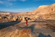 Turchia, Cappadocia, Veduta posteriore della donna in abito rosso passeggiando nel paesaggio roccioso — Foto stock