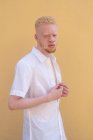 Allemagne, Cologne, Albinos homme en chemise blanche contre mur jaune — Photo de stock