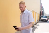 Alemania, Colonia, Albino hombre de camisa blanca con teléfono inteligente - foto de stock