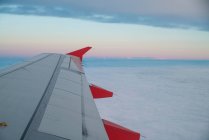 Aile d'avion au-dessus des nuages au coucher du soleil — Photo de stock