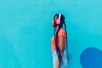 Italie, Milan, Profil de jeune femme avec écouteurs devant le mur bleu — Photo de stock