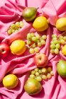 Verschiedene Früchte auf rosa Tischdecke — Stockfoto