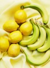 Blick von oben auf Bananen und Zitronen auf gelbem Tuch — Stockfoto