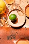 Overhead view of lime on plate and glasses on concrete surface — Stock Photo