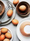 Brown eggs, plates, bowls and egg beater — Stock Photo
