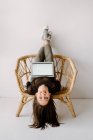 Женщина сидит вверх ногами в кресле с ноутбуком — стоковое фото