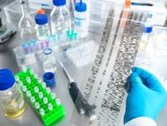 Scientifique tenant un échantillon de gel d'ADN en laboratoire — Photo de stock
