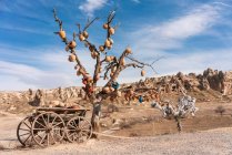 Turquía, Capadocia, Goreme, Árbol de los deseos y carro en el paisaje estéril - foto de stock