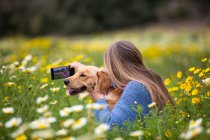 Spain, Mallorca, Woman with Golden Retriever taking selfie in blooming meadow — Stock Photo