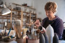 España, Baleares, Mujer pintando cerámica en taller - foto de stock