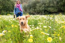 Spain, Mallorca, Smiling woman with Golden Retriever in blooming meadow — Stock Photo