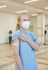 Austria, Vienna, Nurse in face mask with adhesive bandage on arm — Stock Photo