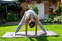 Großbritannien, London, Frau macht Yoga auf dem Rasen vor dem Haus — Stockfoto
