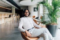 Itália, Retrato de homem sorridente sentado em poltrona em estúdio criativo — Fotografia de Stock