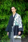 UK, Portrait of young man wearing kimono in park — Stock Photo