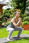 UK, London, Woman doing squats on lawn in front of house — Stock Photo