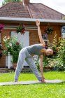 Großbritannien, London, Frau macht Yoga auf dem Rasen vor dem Haus — Stockfoto