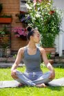 Великобритания, Лондон, Женщина медитирует на газоне перед домом — стоковое фото