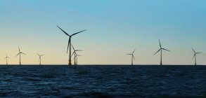 Ветряные турбины в воде против голубого неба — стоковое фото