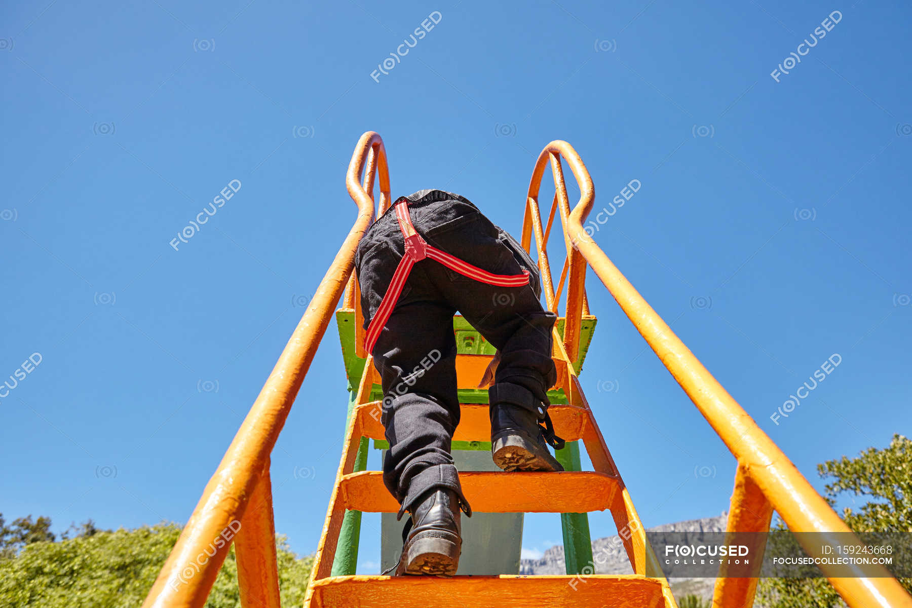 Boy climbing up slide in playground — sunlight, toddler Stock Photo