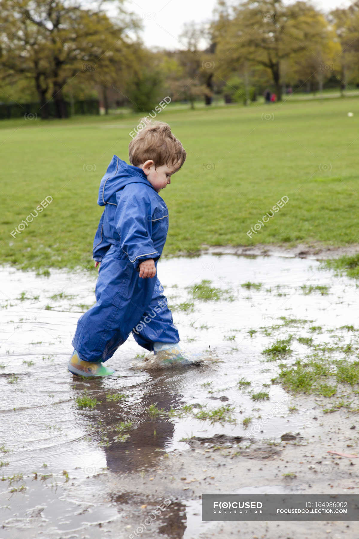 Toddler boy walking in puddle — side view, childhood - Stock Photo ...