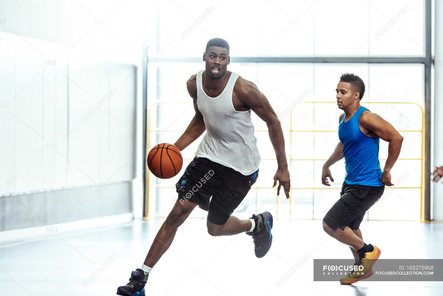 Male basketball players running with ball and defending on basketball court — sport, basketball