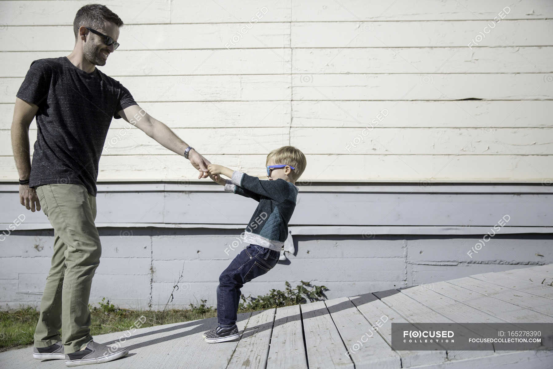 Boy pulling father up wooden ramp — childhood, caucasian - Stock Photo