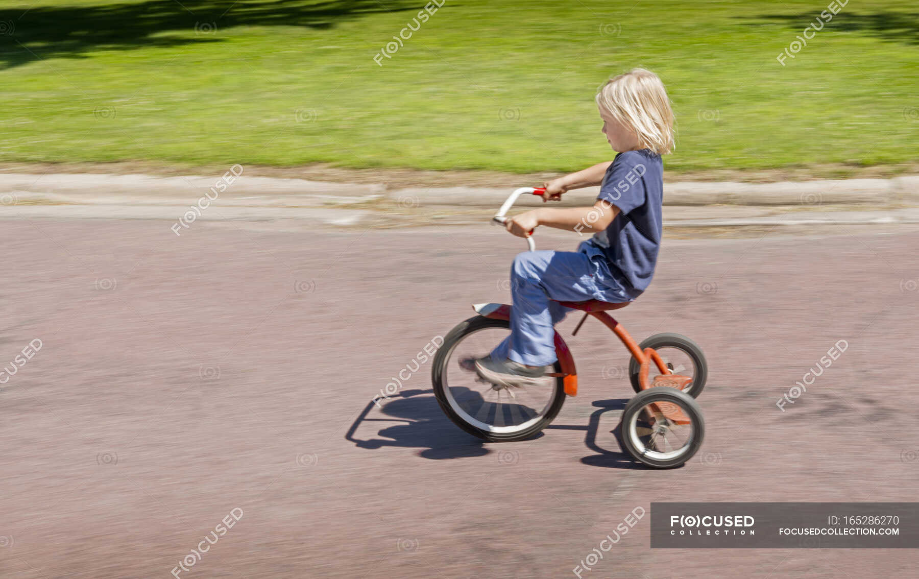 Side view of boy riding tricycle — leisure, outdoors Stock Photo 165286270