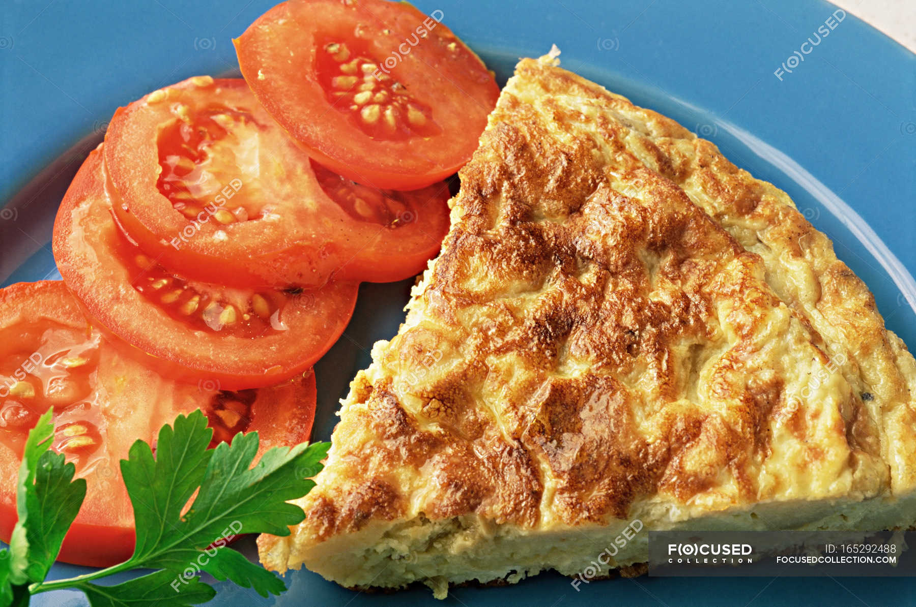 Spanish omelette with tomatoes and herb — portion, blue Stock Photo