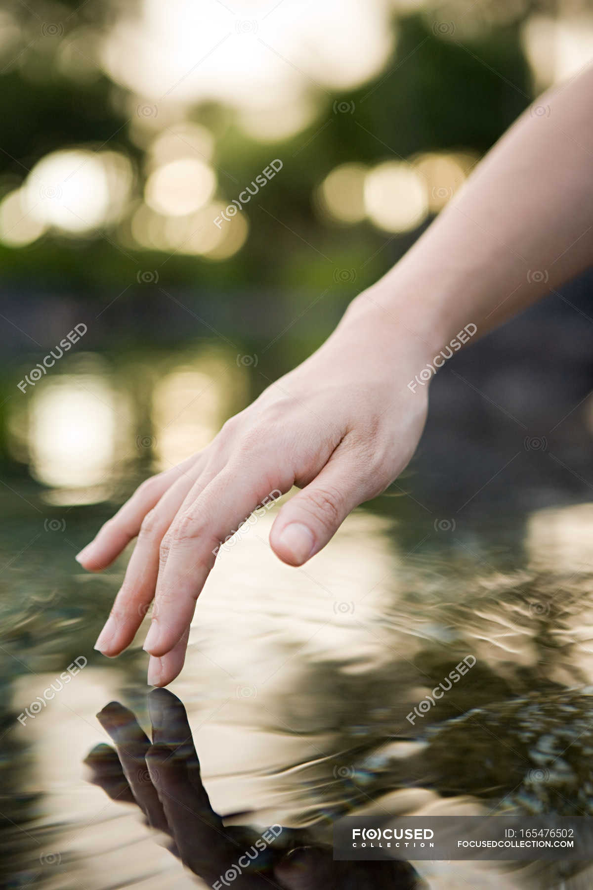 female-hand-touching-water-surface-lake-harmony-stock-photo