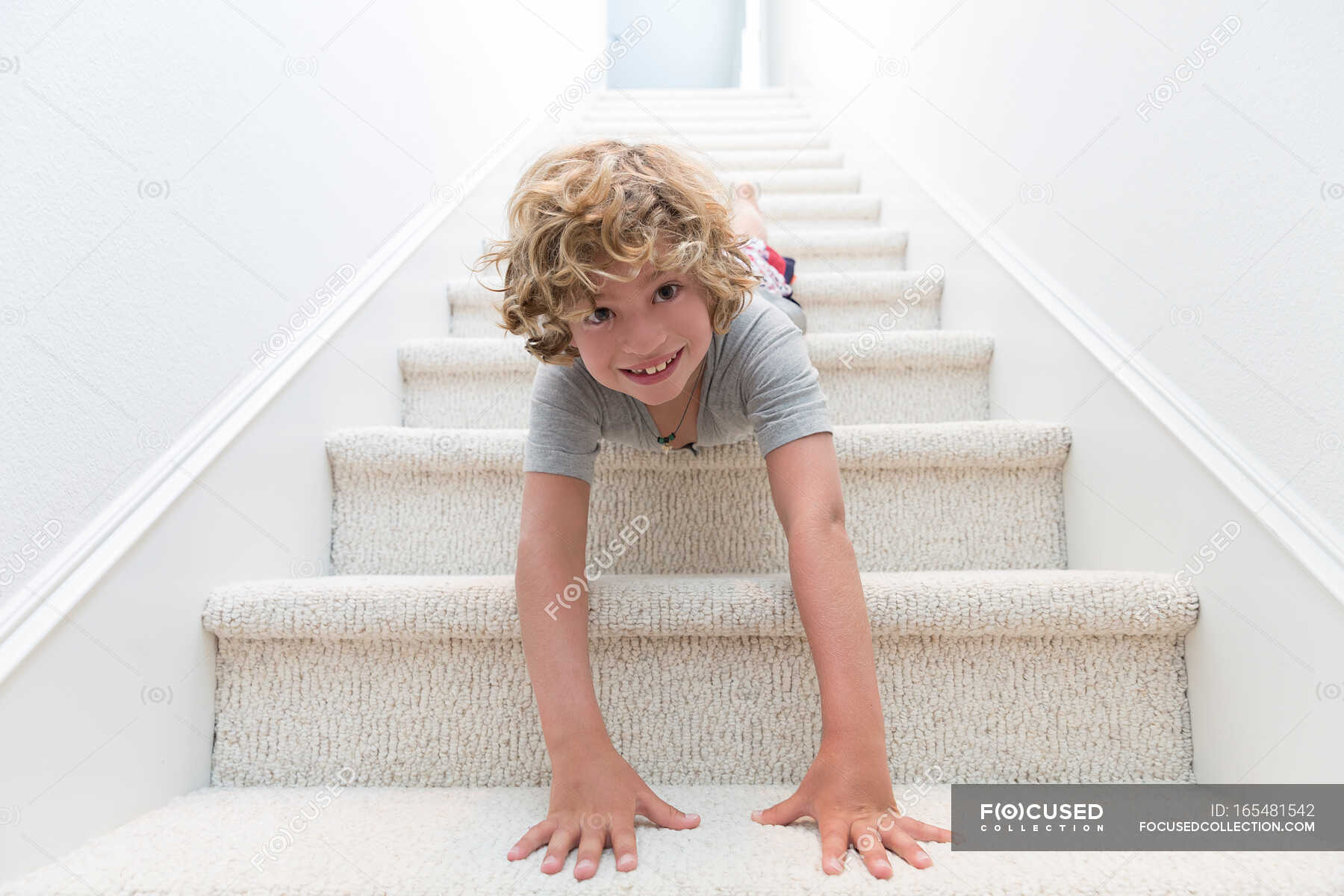 Portrait of boy crawling headfirst down stairs — california usa, Curly ...