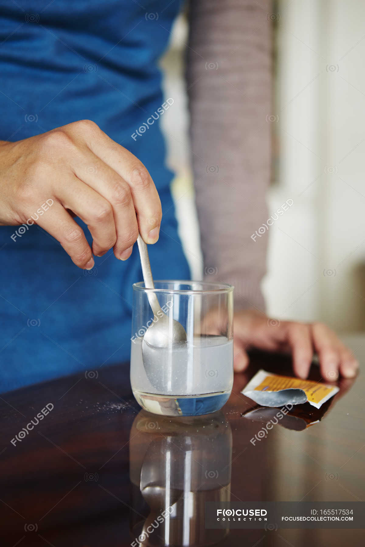 young-woman-mixing-water-soluble-medication-from-sachet-in-glass-of