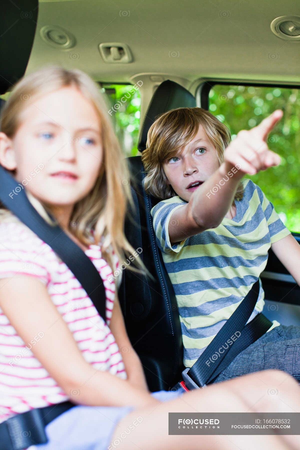 Niños sentados en el asiento trasero del coche — Señalando, mostrando Niños sentados en el asiento trasero del coche — Señalando, mostrando