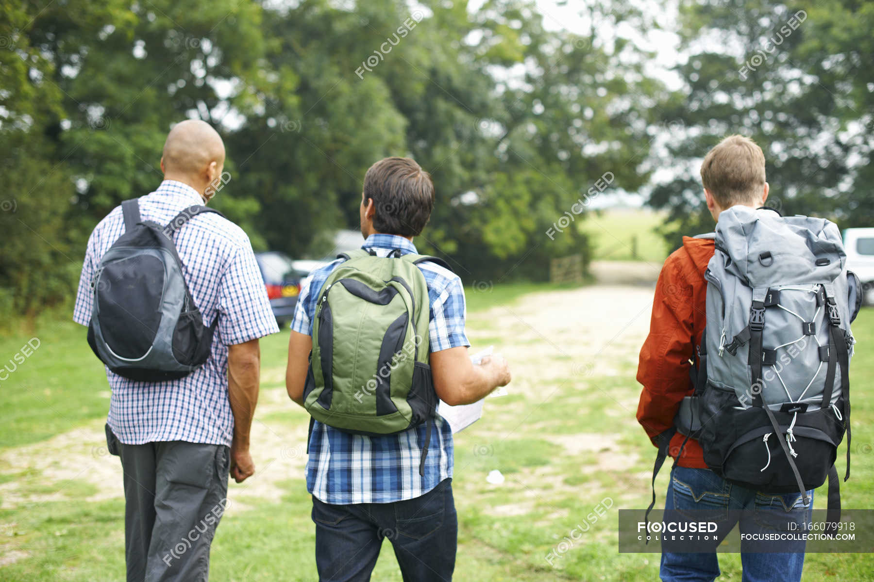 Friends with backpacks walking in field, rear view — Obscured Face ...