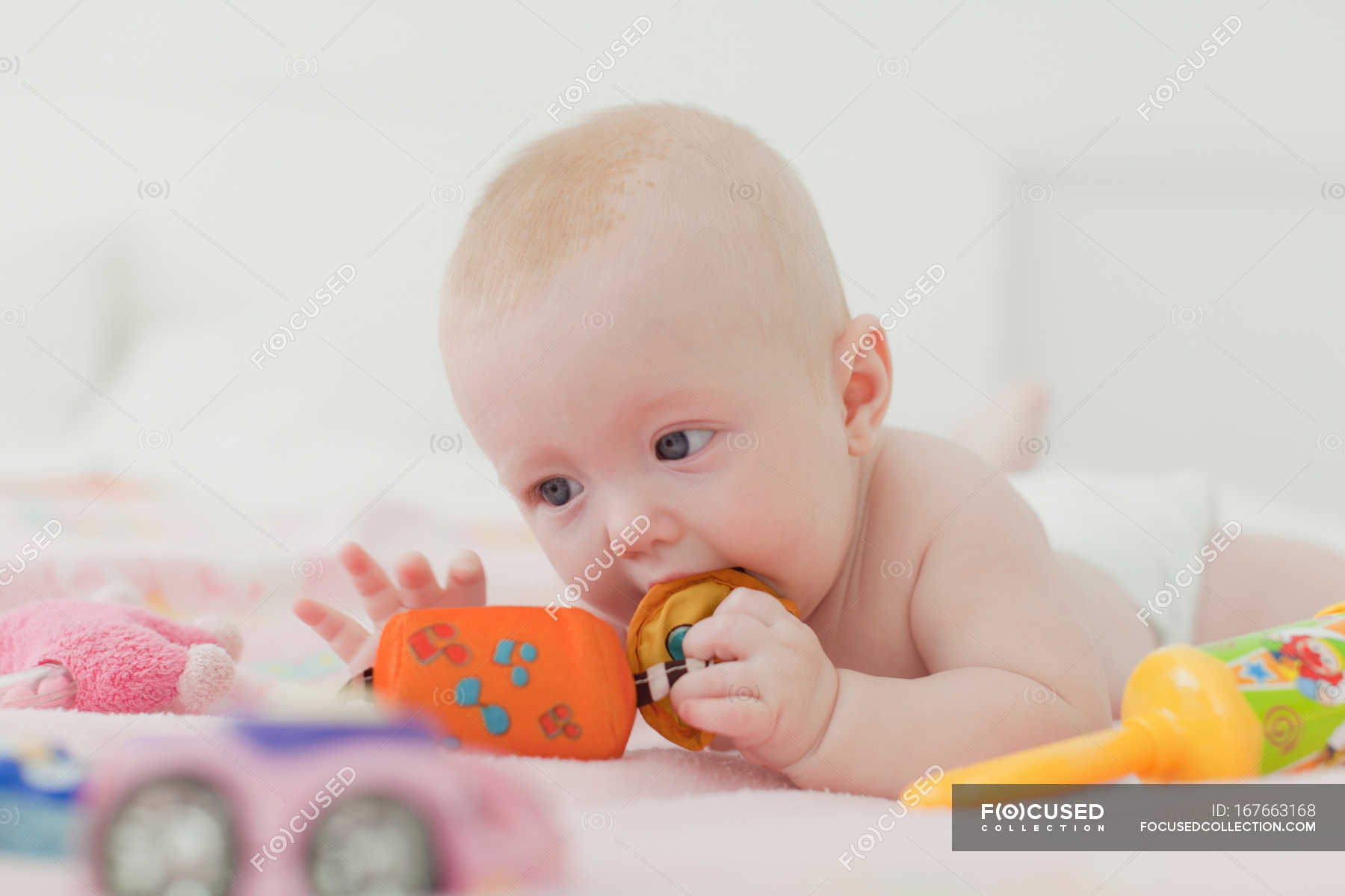 Baby chewing on rattle on blanket — person, beginnings Stock Photo