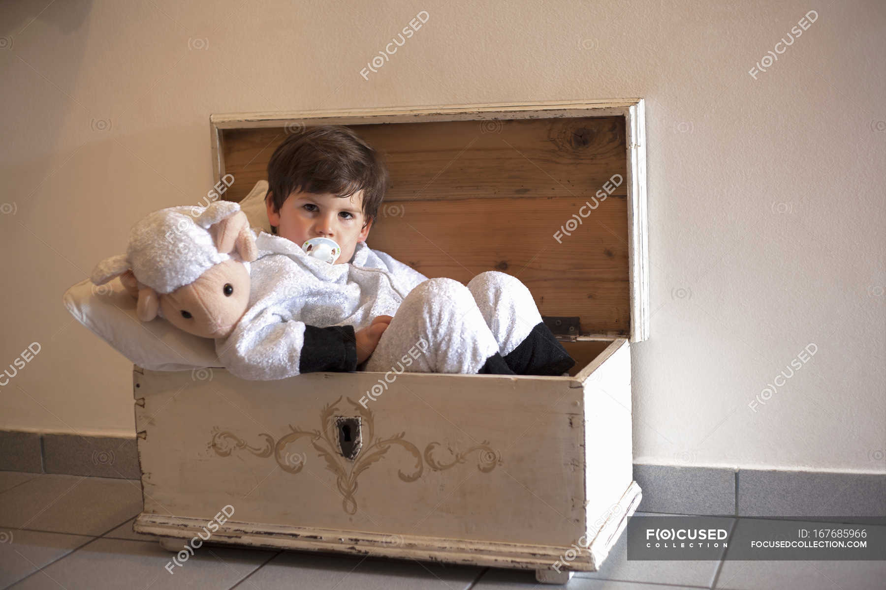 Portrait of male toddler ready for bed in small wooden trunk — stuck
