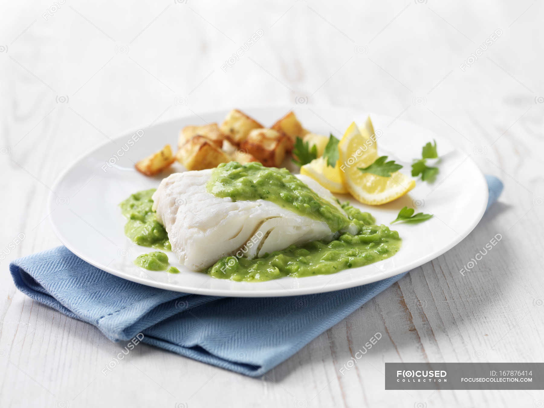 Haddock fish fillet with fried potatoes, minted pea sauce and lemon
