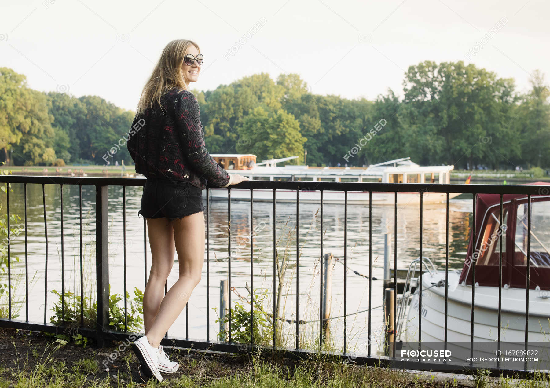 Woman Leaning On Railings At Waterfront Looking Over Shoulder